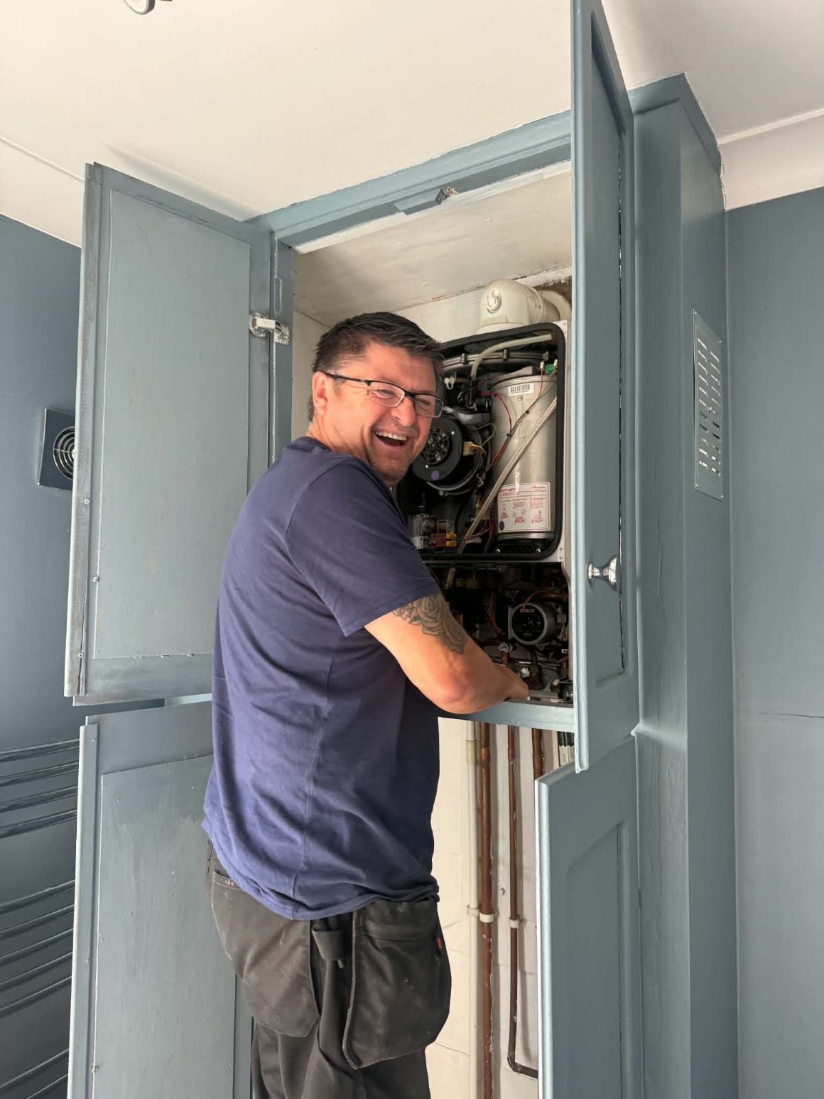 Mark from PlumbLincs, smiling while working on a boiler